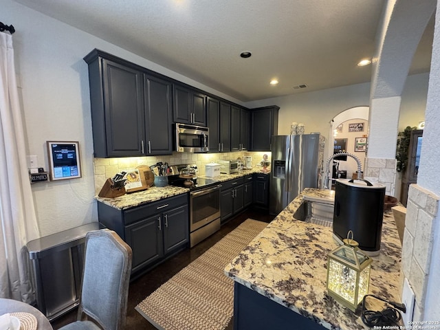 kitchen featuring tasteful backsplash, appliances with stainless steel finishes, and light stone counters