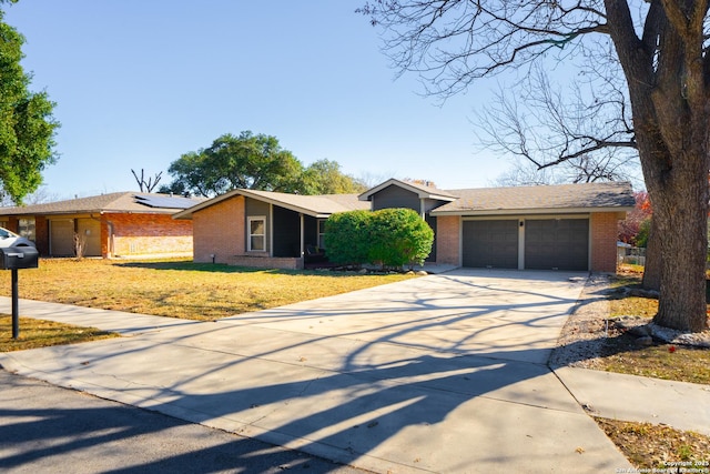 ranch-style home with a garage, a front yard, and solar panels