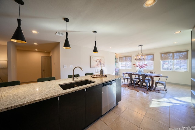 kitchen featuring sink, light tile patterned floors, light stone counters, decorative light fixtures, and stainless steel dishwasher