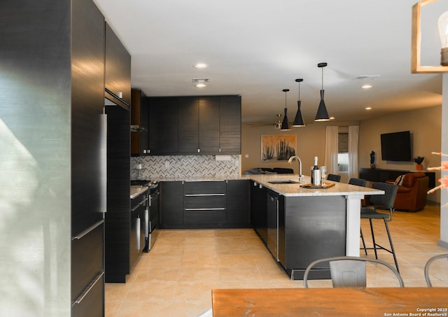 kitchen with sink, a breakfast bar area, decorative light fixtures, fridge, and kitchen peninsula