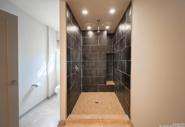 bathroom featuring toilet, tile patterned flooring, and a tile shower