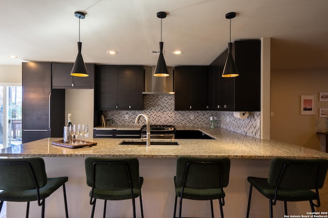 kitchen with tasteful backsplash, sink, pendant lighting, and a breakfast bar