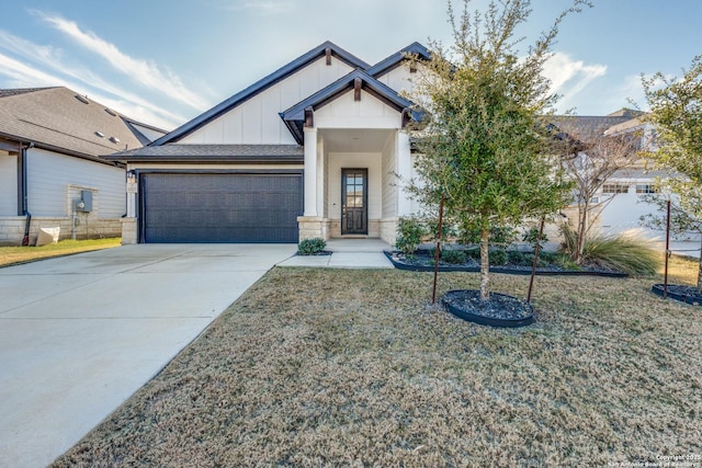 view of front of property featuring an attached garage, concrete driveway, stone siding, board and batten siding, and a front yard