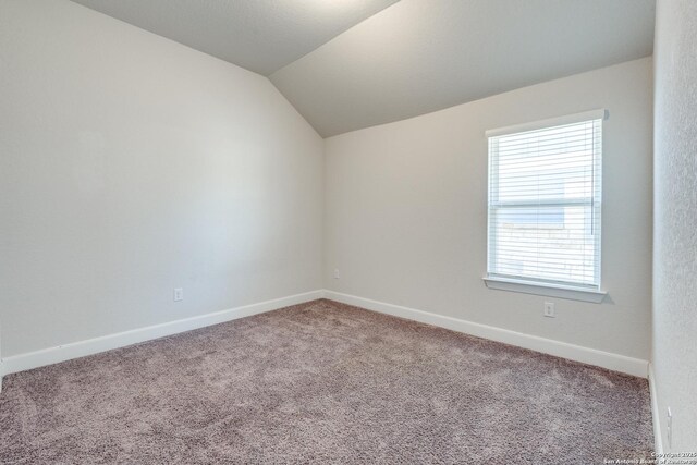 carpeted spare room featuring lofted ceiling