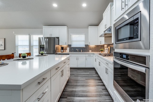 kitchen with a healthy amount of sunlight, decorative backsplash, white cabinets, and appliances with stainless steel finishes