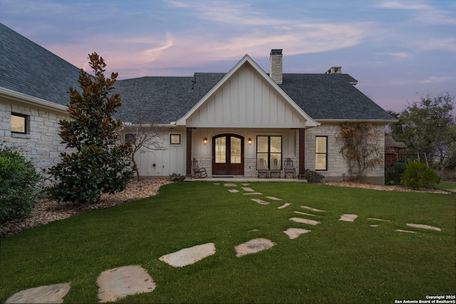 view of front of property with a lawn, french doors, and a porch