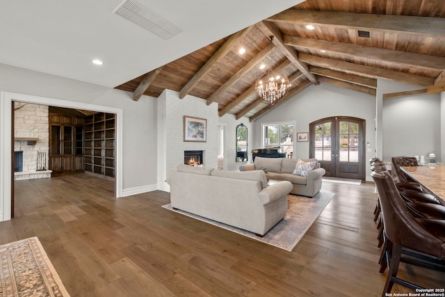 living room featuring french doors, wood ceiling, a brick fireplace, dark hardwood / wood-style floors, and beam ceiling