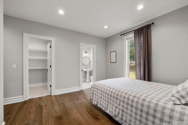 bedroom with hardwood / wood-style flooring, ensuite bathroom, a spacious closet, and a closet