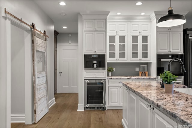 kitchen featuring white cabinetry, beverage cooler, a barn door, and black oven