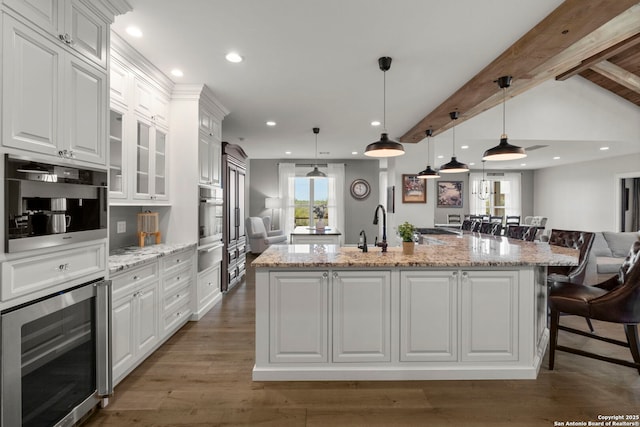 kitchen featuring pendant lighting, a breakfast bar, a center island with sink, and white cabinets