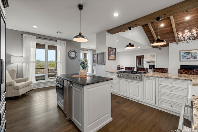 kitchen with pendant lighting, vaulted ceiling with beams, white cabinets, stainless steel gas cooktop, and light stone countertops