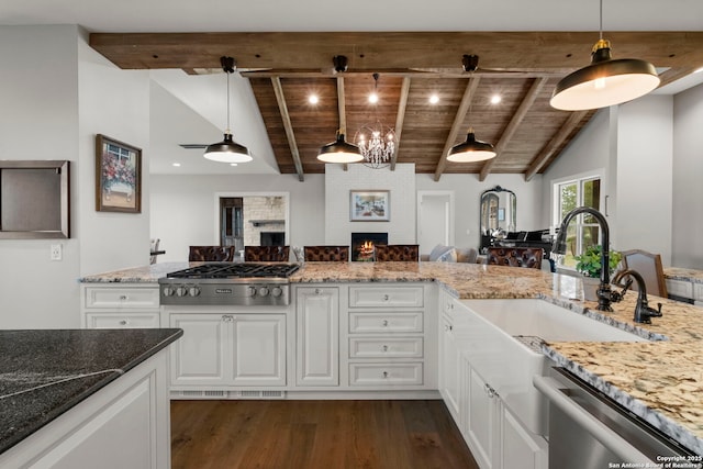 kitchen featuring hanging light fixtures, wooden ceiling, a large fireplace, appliances with stainless steel finishes, and white cabinets