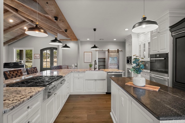 kitchen with a barn door, sink, white cabinets, and appliances with stainless steel finishes