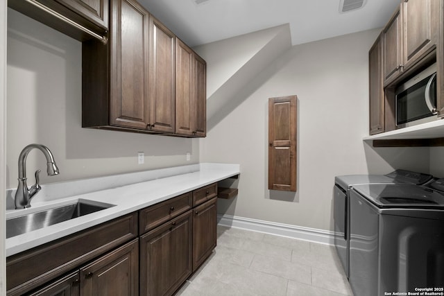 kitchen with sink, dark brown cabinets, washer and clothes dryer, and light tile patterned floors