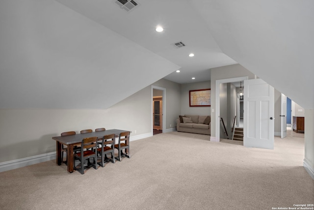 dining space with light carpet and vaulted ceiling