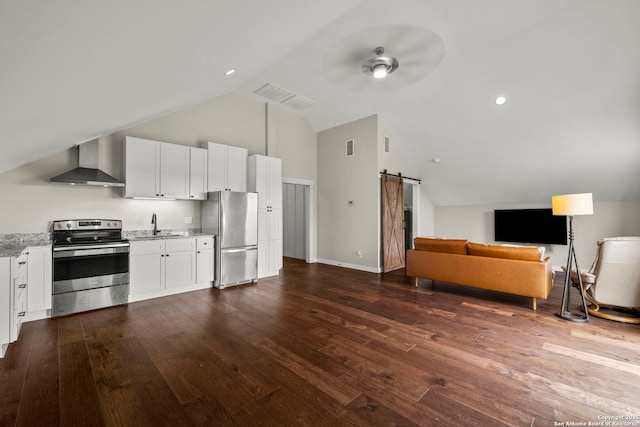 kitchen with a barn door, white cabinetry, appliances with stainless steel finishes, and wall chimney range hood