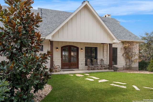 view of front of home with a front lawn, covered porch, and french doors