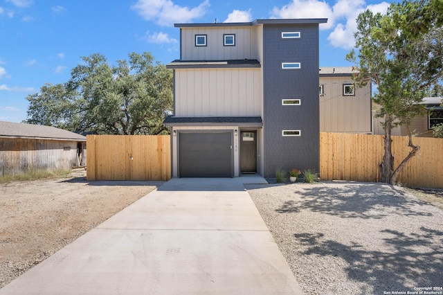 view of front of home featuring a garage, concrete driveway, fence, and a gate