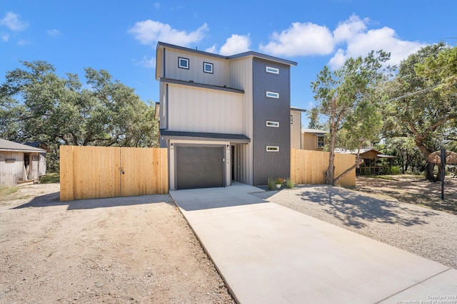 contemporary home featuring driveway, an attached garage, and fence