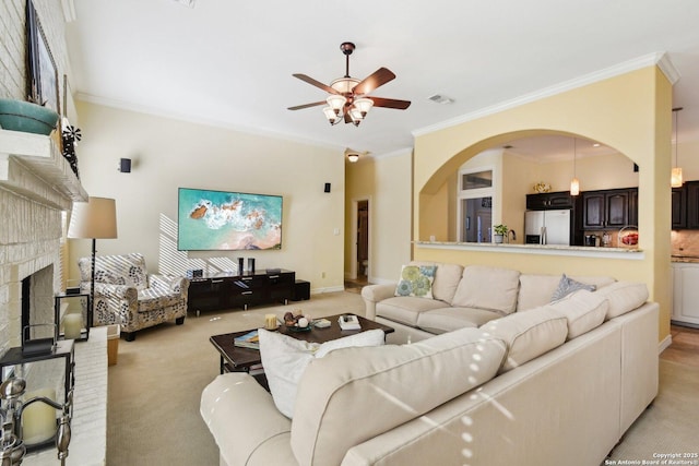 living room with crown molding, light colored carpet, ceiling fan, and a fireplace