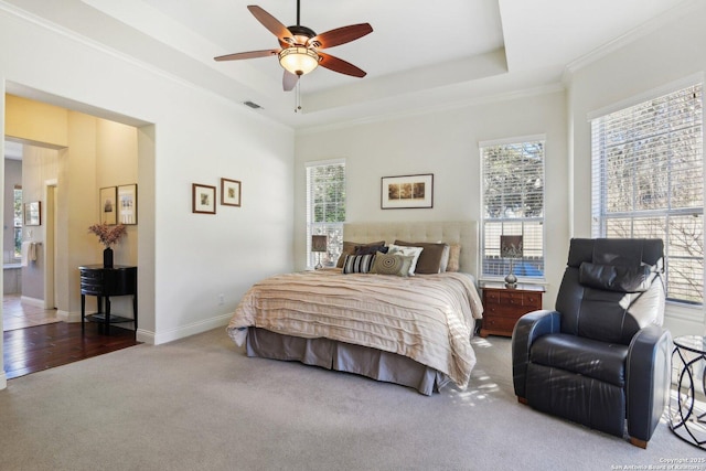 bedroom featuring ceiling fan, ornamental molding, a raised ceiling, and carpet