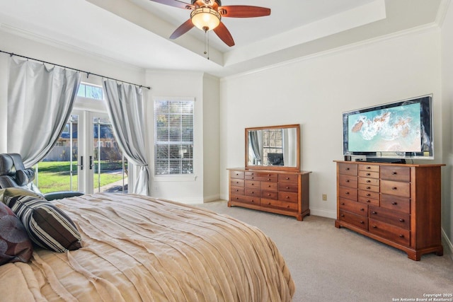 bedroom with access to exterior, a tray ceiling, ornamental molding, light colored carpet, and french doors