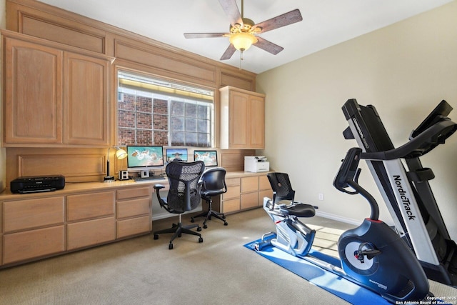 office featuring ceiling fan, light colored carpet, and built in desk