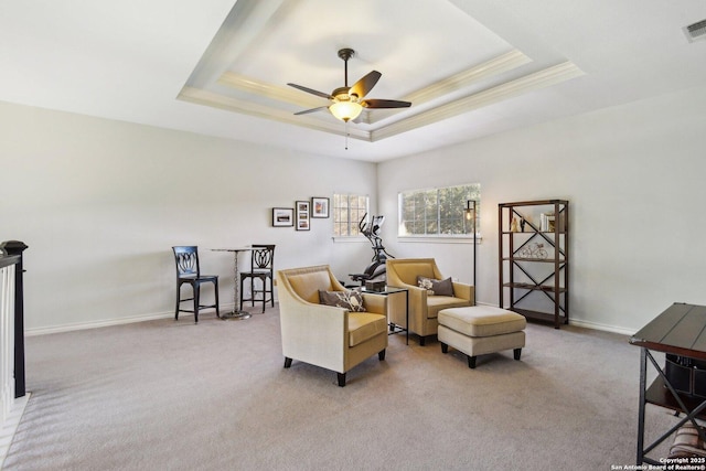 sitting room featuring a raised ceiling, ornamental molding, light carpet, and ceiling fan