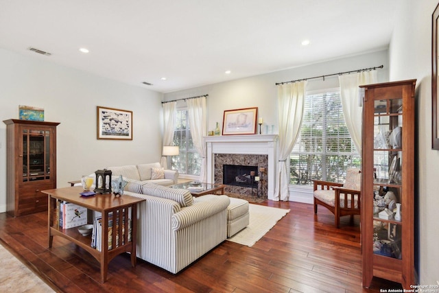 living room featuring a high end fireplace, a wealth of natural light, and dark hardwood / wood-style flooring