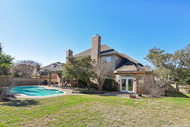 back of house with a patio, a lawn, a pergola, a fenced in pool, and french doors