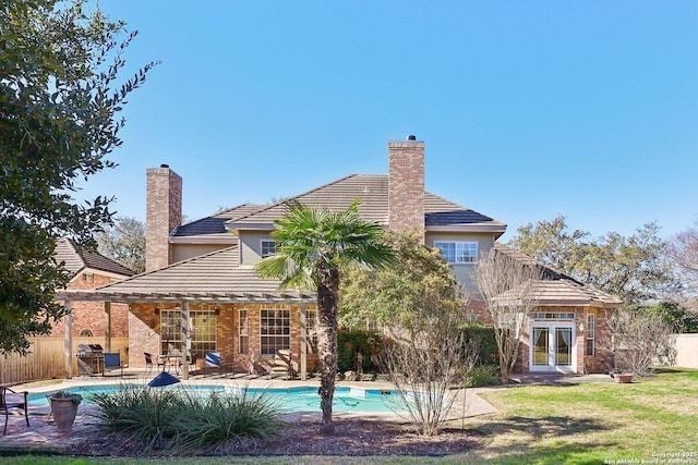 rear view of property featuring a fenced in pool, a yard, and french doors