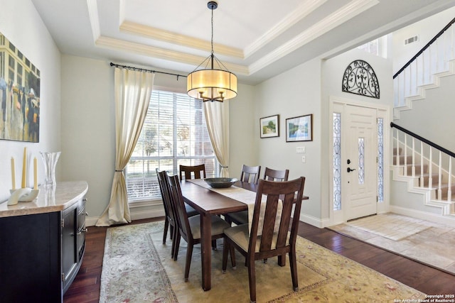 dining room featuring crown molding, a tray ceiling, dark hardwood / wood-style flooring, and an inviting chandelier