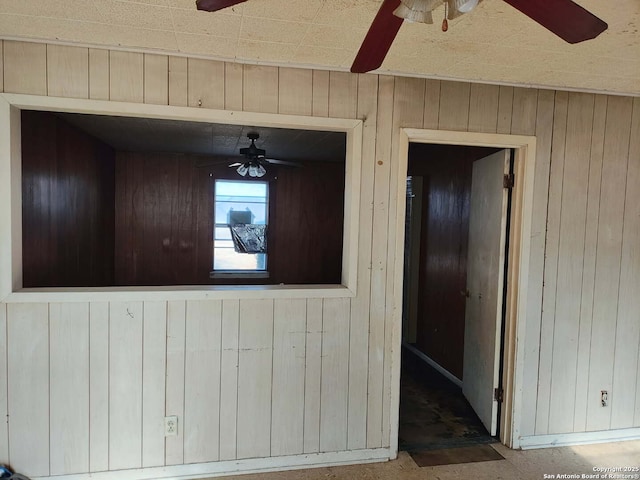 interior space with ceiling fan and wood walls