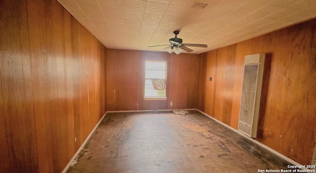 empty room featuring ceiling fan and wood walls