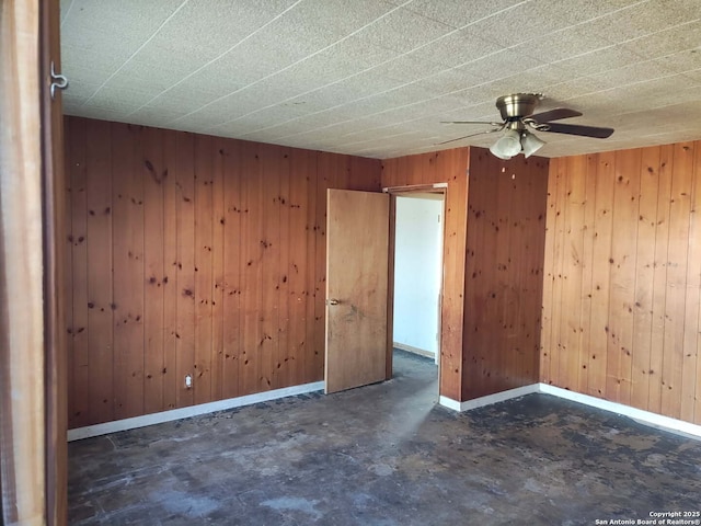 empty room with ceiling fan and wood walls