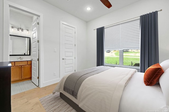 bedroom featuring connected bathroom, sink, light hardwood / wood-style flooring, and ceiling fan