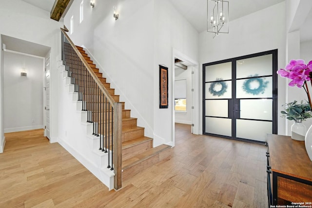 entrance foyer with a towering ceiling, a chandelier, and light hardwood / wood-style flooring