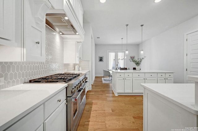 kitchen featuring light hardwood / wood-style flooring, double oven range, light stone countertops, white cabinets, and decorative light fixtures