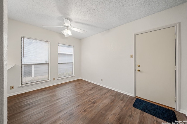 empty room with ceiling fan, dark hardwood / wood-style floors, and a textured ceiling