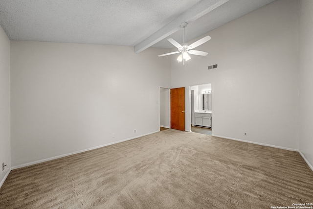 unfurnished bedroom with ensuite bathroom, high vaulted ceiling, beam ceiling, light colored carpet, and a textured ceiling