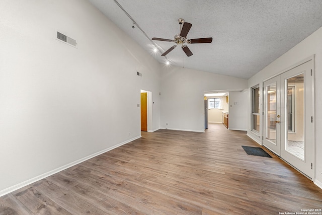 empty room with ceiling fan, light hardwood / wood-style flooring, french doors, and a textured ceiling