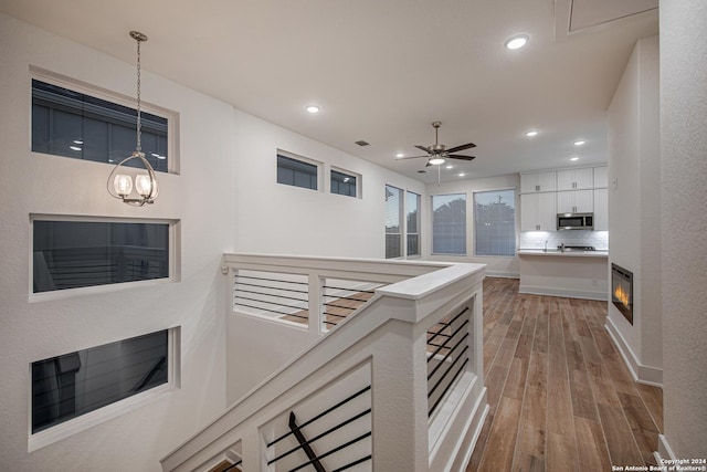 corridor with an inviting chandelier and light hardwood / wood-style floors