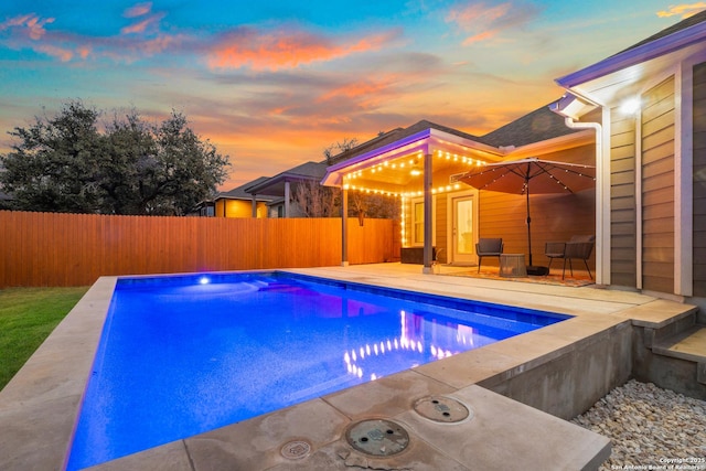 pool at dusk with a patio area