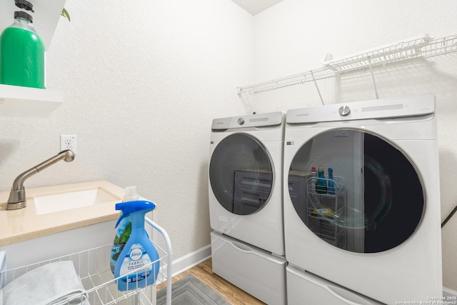 clothes washing area featuring sink, wood-type flooring, and washing machine and dryer