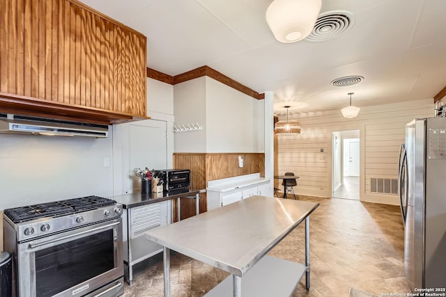 kitchen with stainless steel appliances, wooden walls, custom range hood, and hanging light fixtures