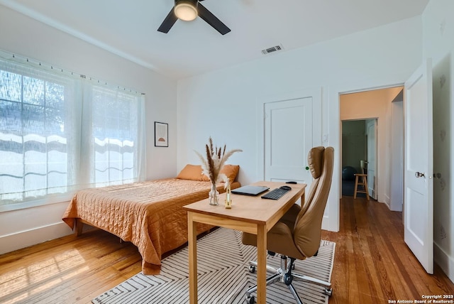 bedroom with multiple windows, wood-type flooring, and ceiling fan