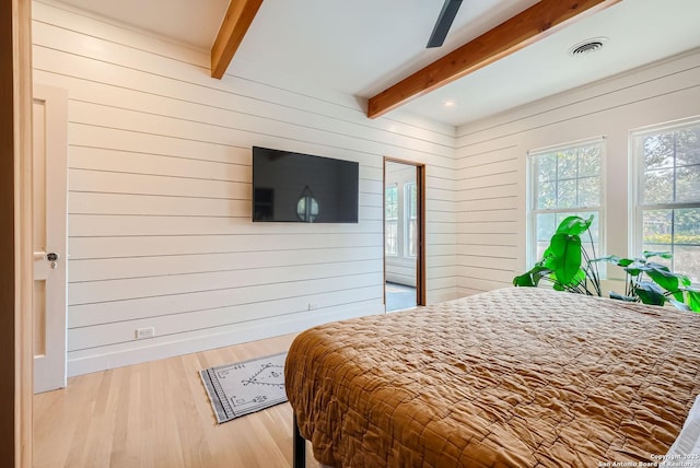 bedroom featuring beam ceiling, wood-type flooring, and wood walls