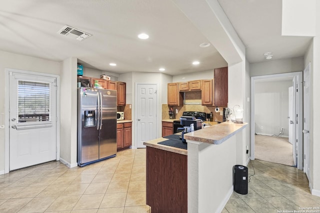 kitchen featuring stainless steel refrigerator with ice dispenser, backsplash, light tile patterned flooring, and electric range