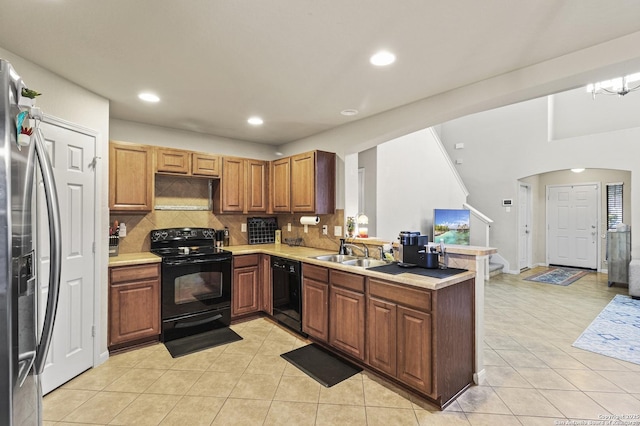 kitchen with sink, black appliances, light tile patterned floors, kitchen peninsula, and backsplash