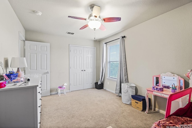 carpeted bedroom featuring ceiling fan and a closet